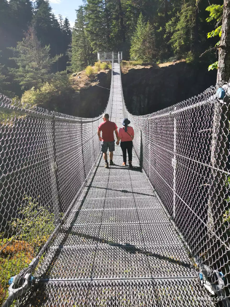 People crossing a long bridge over the Elk Falls - Campbell River, Vancouver Island